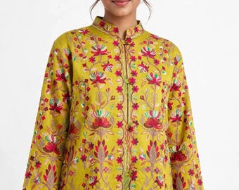 May include: A chartreuse long-sleeved tunic featuring a mandarin collar and a front button closure. The garment is decorated with intricate floral embroidery in shades of red, pink, white, and green across the entire front surface.