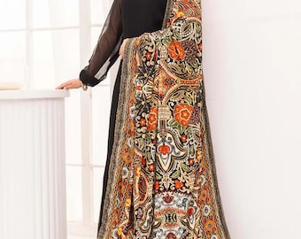 May include: A black dress with sheer sleeves and a decorative neckline. The dress is paired with a shawl featuring a colorful paisley pattern in shades of orange, red, and gold. The shawl drapes over the dress.