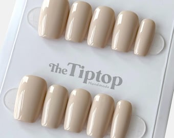 May include: A set of ten beige press-on nails in various sizes, arranged on a white display card. The nails have a glossy finish and a rounded shape. The text "The Tiptop Handmade" is printed on the card.