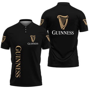May include: Black polo shirt featuring the Guinness logo and harp emblem in gold. The shirt has the word "GUINNESS" printed vertically on the front and the brand name on the back. The design includes the harp emblem on the sleeves.
