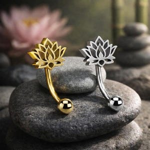 Può includere: Due gioielli per il corpo a barra curva, uno color oro e uno color argento, ciascuno caratterizzato da un design a fiore di loto ritagliato sulla parte superiore e una sfera liscia e rotonda all'estremità inferiore dell'asta metallica curva.
