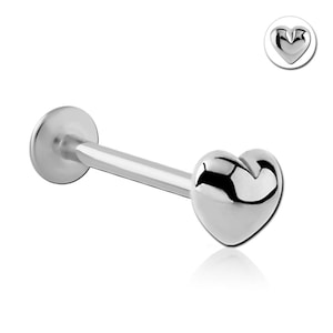 Könnte beinhalten: Ein silberfarbener Lippenpiercing-Stecker mit herzförmigem Ende. Der Stecker hat eine flache, runde Rückseite und einen geraden Stab, der zum Herzen führt. Ein kleineres, kreisförmiges Bild des Herzens befindet sich oben rechts.