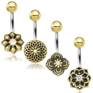 Könnte beinhalten: Vier Bauchnabelpiercings mit goldfarbenen Oberteilen und dekorativen Unterteilen. Die Designs umfassen eine Blume, einen Filigrankreis, eine vierblättrige Blume und eine mehrblättrige Blume. Jedes hat einen silberfarbenen Stab und einen kleinen, runden, weißen oder klaren Edelstein.