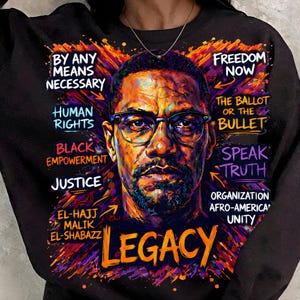 May include: Black sweatshirt featuring a vibrant portrait with glasses and beard. Text includes "By Any Means Necessary," "Human Rights," "Black Empowerment," "Legacy," and other phrases.