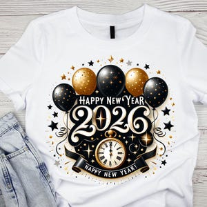 May include: White t-shirt featuring a festive New Year's design. The graphic includes gold and black balloons, stars, and the text "Happy New Year 2026". A gold pocket watch is also featured in the design.
