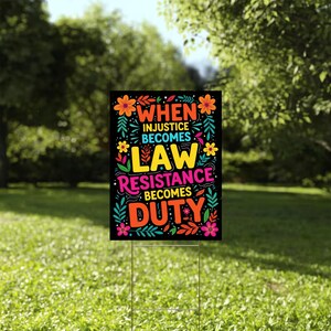 May include: A black yard sign featuring the text "WHEN INJUSTICE BECOMES LAW RESISTANCE BECOMES DUTY" in vibrant colours. The sign is adorned with floral and leaf designs in orange, yellow, pink, and teal. It is mounted on a metal stake in a grassy garden.