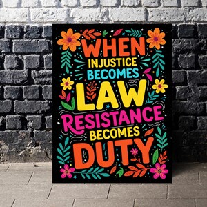 May include: A black poster with vibrant text and floral decorations. The text states "WHEN INJUSTICE BECOMES LAW RESISTANCE BECOMES DUTY" in bright colours. Orange, yellow, pink, and green flowers and leaves adorn the text.