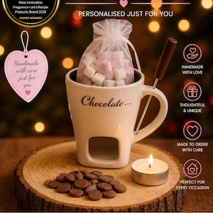 May include: A cream-coloured chocolate fondue mug with a handle, filled with marshmallows, and a small candle. The mug sits on a wooden slice with chocolate chips. Text includes "Made with love" and "Handmade with care".