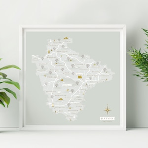 Peut inclure: Une carte stylisée du Devon, en Angleterre, avec un fond gris clair et des accents dorés. La carte montre l'emplacement de diverses villes et villages, dont Plymouth, Exeter et Barnstaple. La carte est encadrée dans un cadre blanc.