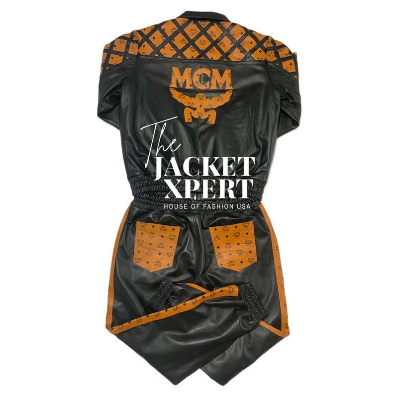 May include: Black leather jacket and matching pants set with orange MCM logo pattern accents. The jacket features the MCM logo on the back and the text "The JACKET XPERT HOUSE OF FASHION USA". The pants have pockets with the MCM logo.