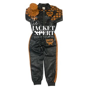 May include: Black leather-look tracksuit set with brown accents and a matching bucket hat. The jacket and pants feature the MCM logo. The set includes a zip-up jacket, pants, and a bucket hat. The text "The Jacket Xpert" is visible.