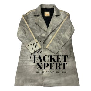 May include: A light gray suede trench coat with a classic design. The coat features a notched collar, a double-breasted closure, and a matching belt. The text "The Jacket Xpert House of Fashion USA" is printed on the coat.