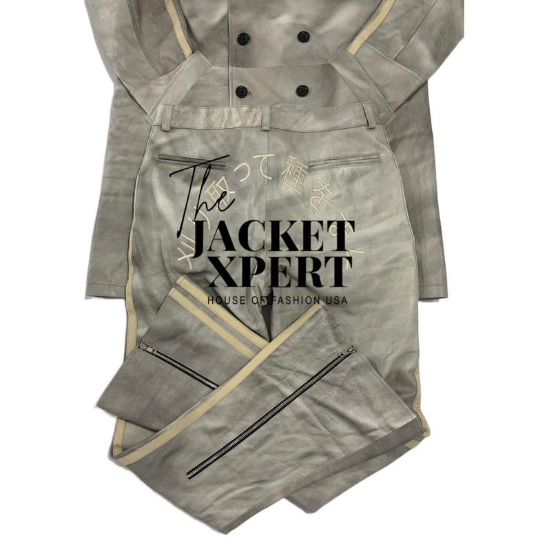 May include: A light gray two-piece suit featuring a jacket and pants. The jacket has a double-breasted design with black buttons and cream-colored stripes. The pants have cream-colored stripes down the sides and black zippers at the ankles. The text "The JACKET XPERT" is visible.