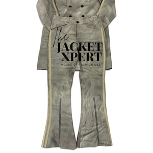 May include: A two-piece gray suede outfit featuring a jacket and flared pants. The jacket has a button-up front, and the pants have zippers at the ankles and cream-colored stripes down the sides. The text "The JACKET XPERT HOUSE OF FASHION USA" is visible.