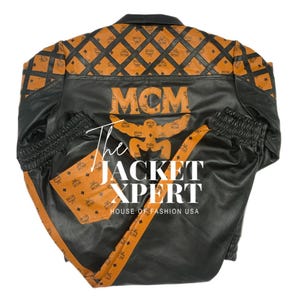 May include: Black and orange leather jacket and pants set. The jacket features a diamond pattern on the shoulders and the MCM logo. The pants have an orange stripe down the side. The text "The Jacket Xpert" is visible.