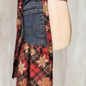 A mannequin wearing a red and black plaid apron with a gummy bear pattern, and a black lace skirt.