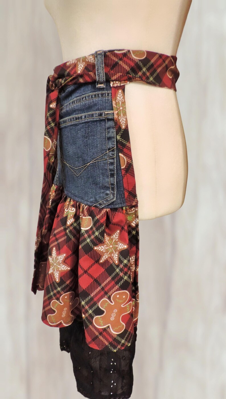 A mannequin wearing a red and black plaid apron with a gummy bear pattern, and a black lace skirt.