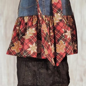 A skirt made from a denim apron and a lace overlay, featuring a plaid pattern with gingerbread man motifs.