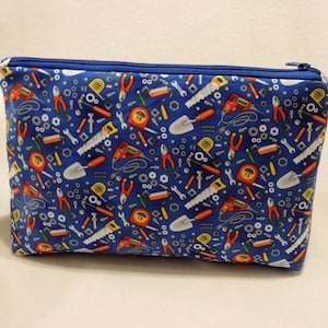 Puede incluir: Una bolsa azul con cremallera con un patr&oacute;n de herramientas, incluyendo llaves, destornilladores, martillos y cintas m&eacute;tricas.