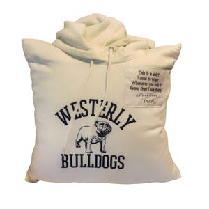 May include: A cream-colored hoodie repurposed into a square pillow. The front features a dark blue graphic of a bulldog with the text "WESTERLY BULLDOGS" and a rectangular patch with the embroidered text "This is a shirt I used to wear Whenever you hold it Know that I am there, Lots of Love, Mom."