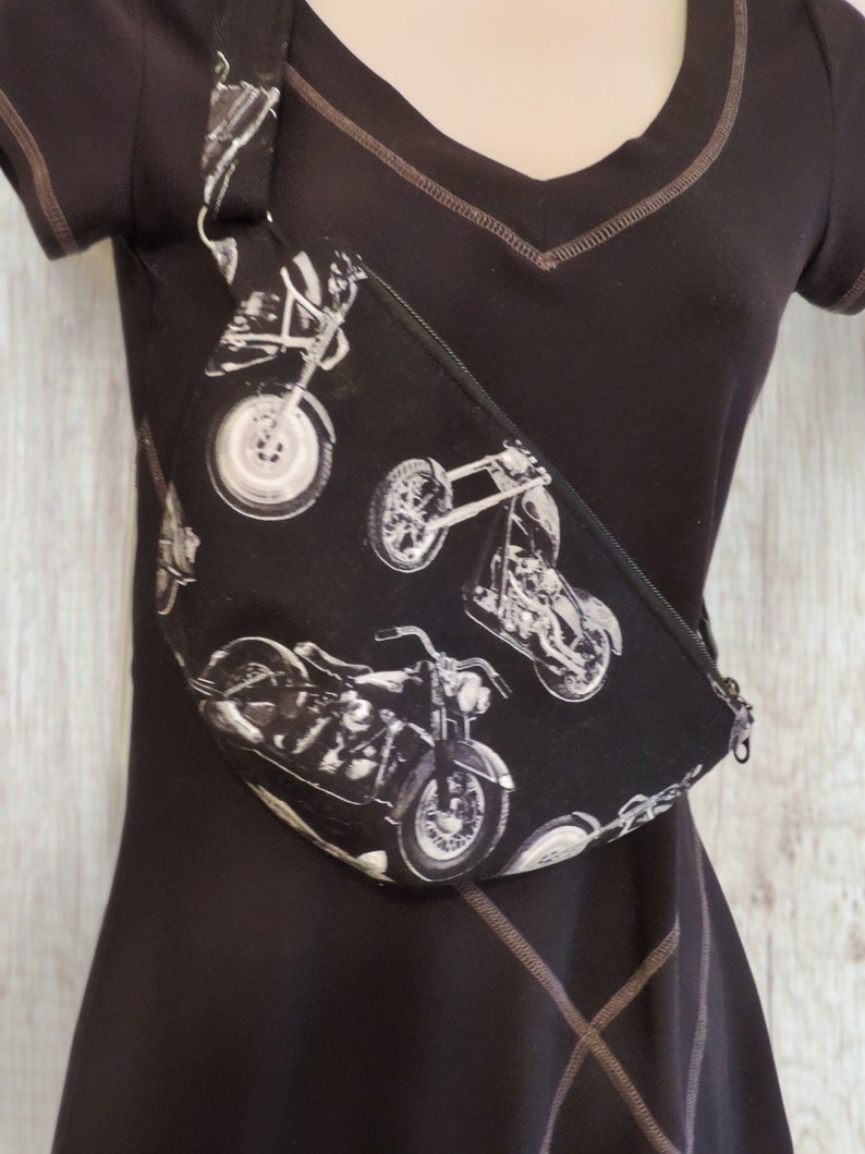 May include: A black fanny pack with a white motorcycle print. The pack has a long adjustable strap.