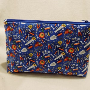 Puede incluir: Una bolsa azul con cremallera con un patr&oacute;n de varias herramientas, incluyendo llaves, destornilladores, martillos, alicates y cintas m&eacute;tricas.