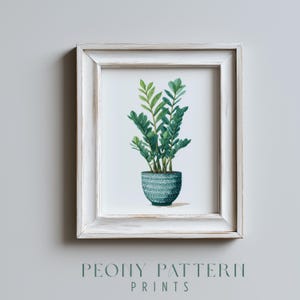 Puede incluir: Una impresión enmarcada con una ilustración en acuarela de una planta ZZ en una maceta texturizada de color turquesa. La planta tiene hojas verdes exuberantes. El marco es blanco con un acabado envejecido. El texto "PEONY PATTERN PRINTS" está en la parte inferior.