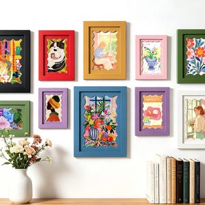 May include: A gallery wall arrangement featuring ten rectangular frames in various colours, including black, red, yellow, pink, green, purple, blue, and white. Each frame contains a unique illustration with a scalloped inner border design.