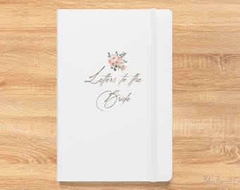 May include: A white journal with the text "Letters to the Bride" in elegant script. A floral design with pink and green accents is above the text. The journal has a matching elastic band.