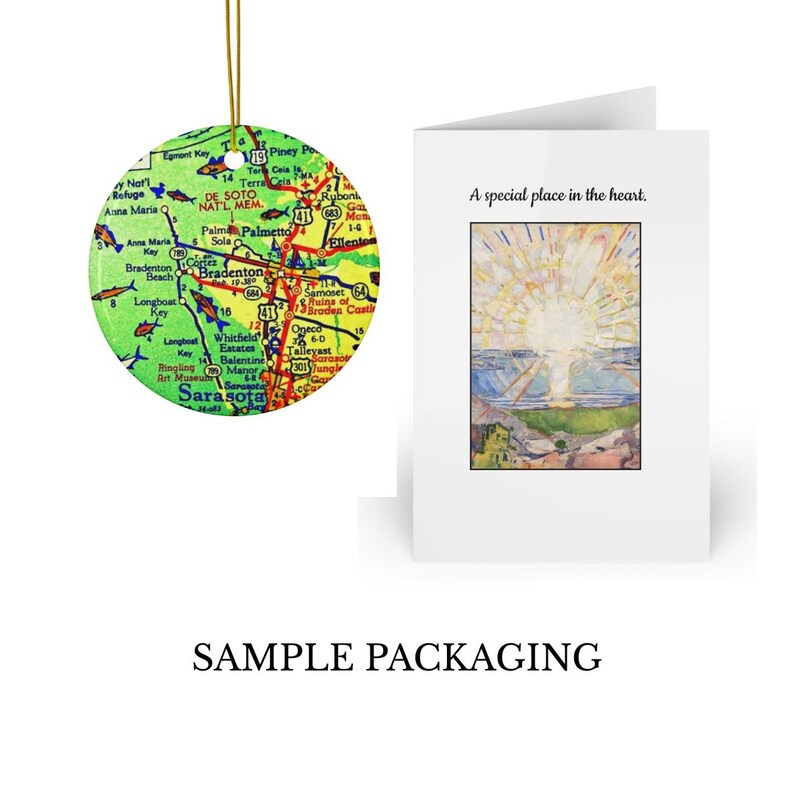 a colorful map ornament hanging next to a greeting card with a painting of a landscape.