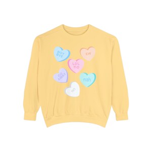 May include: Yellow sweatshirt with a graphic of candy conversation hearts with phrases like "Boy Bye", "Ew", "Lol No", "Go Away", "Nah", and "No".