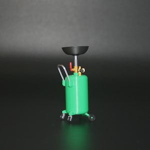 Op de afbeelding: Een kleine groene olieaftapper met een zwarte trechter en een zilveren handvat. De olieaftapper heeft wielen en messing fittingen. De achtergrond is donkergrijs.