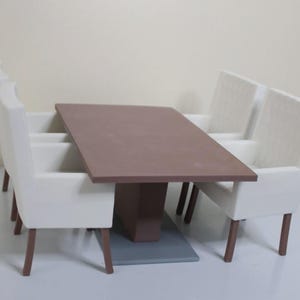 May include: A miniature dining set featuring a rectangular brown table and four white upholstered chairs. The table has a brown pedestal base and sits on a gray platform. The chairs have brown legs.