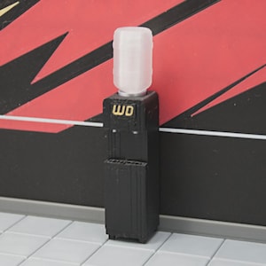 Puede incluir: Un pequeño enfriador de agua negro con una parte superior blanca. El enfriador tiene las letras "WD" en dorado en la parte delantera. El fondo es rojo y negro con detalles blancos.