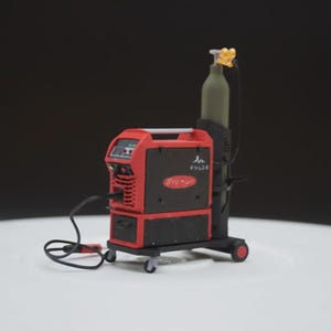 Op de afbeelding: Een rood-zwarte lasmachine met een groene gasfles. De machine heeft een digitaal display en de tekst "Fronius". De lasmachine staat op een onderstel met wielen en een zwarte kabel.