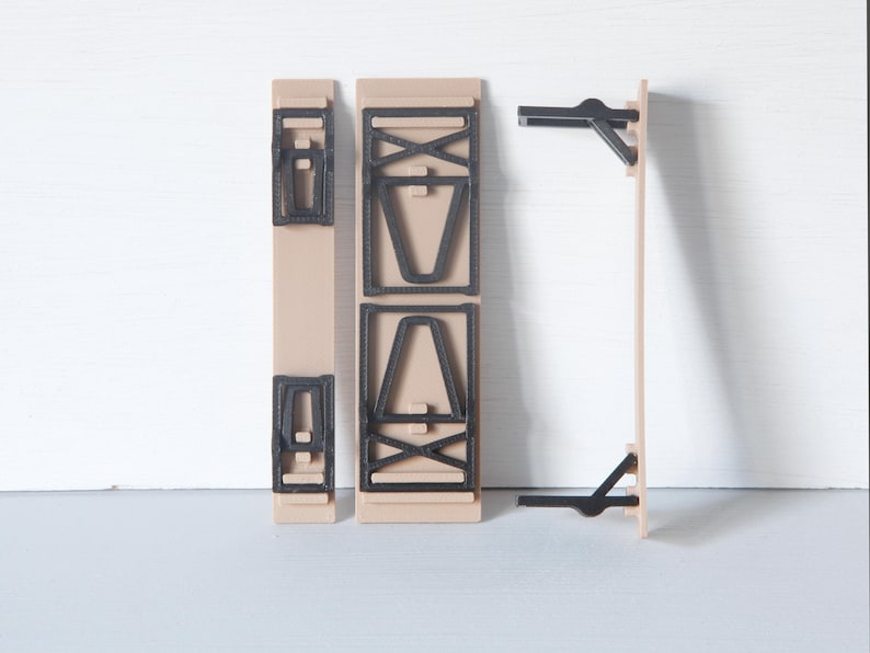 May include: A disassembled wooden table with black accents. The table components are beige with black geometric designs and supports. The pieces are arranged against a white background, showcasing the table's construction.