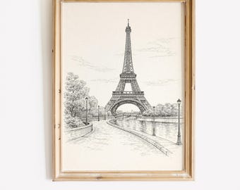 May include: A framed pen and ink drawing of the Eiffel Tower in Paris. The artwork is in black and white and shows the famous landmark with a pathway, trees, and street lamps. The frame is a light wood colour.