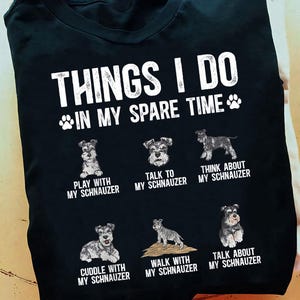Peut inclure: T-shirt noir avec l'inscription blanche "THINGS I DO IN MY SPARE TIME". En dessous, six illustrations de chiens Schnauzer avec des phrases comme "Jouer avec mon Schnauzer" et "Parler de mon Schnauzer".