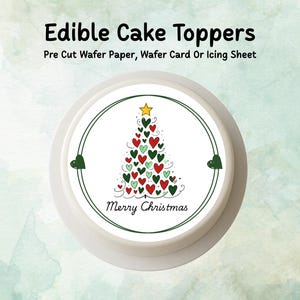 Puede incluir: Adorno comestible para pastel con diseño de árbol de Navidad hecho de corazones rojos, verdes y blancos, coronado por una estrella amarilla. Las palabras "Merry Christmas" están escritas debajo. Fondo blanco.