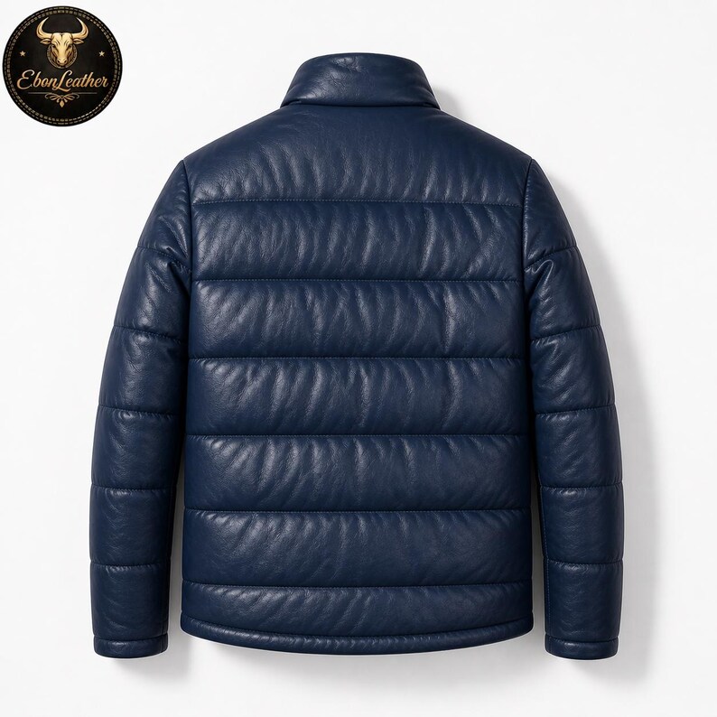 K&ouml;nnte beinhalten: Marineblaue Lederjacke mit Steppdesign. Die Jacke hat einen Stehkragen und lange &Auml;rmel. Das Ebon Leather-Logo ist in der oberen linken Ecke sichtbar.