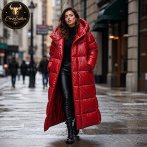Könnte beinhalten: Ein langer, leuchtend roter Steppmantel mit Kapuze. Der Mantel wird über einer schwarzen Hose und Stiefeln getragen. Das Ebon Leather-Logo ist oben links sichtbar. Der Mantel ist ein bodenlanges Design.