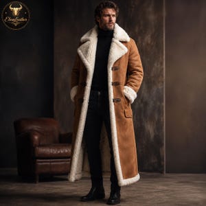 Könnte beinhalten: Ein langer, brauner Shearling-Mantel mit cremefarbenem Shearling-Futter und -Besatz. Der Mantel hat drei Knebelverschlüsse und zwei Taschen. Das Model trägt einen schwarzen Rollkragenpullover und eine schwarze Jeans. Der Mantel ist von EbonLeather.
