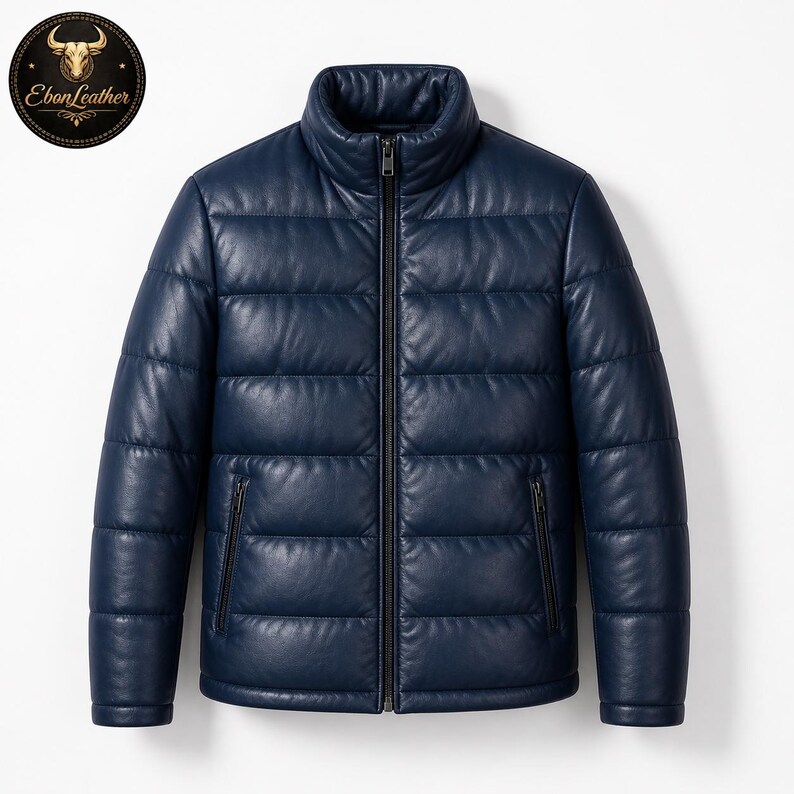 K&ouml;nnte beinhalten: Marineblaue Leder-Steppjacke mit hohem Kragen und durchgehendem Rei&szlig;verschluss. Die Jacke hat ein gestepptes Design und zwei Seitentaschen mit Rei&szlig;verschl&uuml;ssen. Das Ebon Leather-Logo ist oben links sichtbar.
