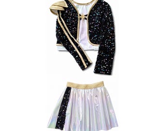 May include: A two-piece outfit consisting of a black long-sleeve bolero jacket covered in iridescent sequins with gold trim and a shoulder accent, paired with a white iridescent pleated skirt featuring a vertical black sequin stripe.