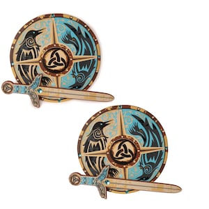 May include: Two wooden Viking shield and sword sets. The shields are round with a raven and wolf design in black and teal, with a central knot symbol. The swords are light brown with teal accents.