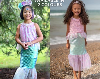 May include: Two mermaid costumes featuring sequined sleeveless tops and scale-patterned skirts with tulle hems. The text AVAILABLE IN 2 COLOURS is centered at the top. One costume is purple and teal, the other is pink and light blue.