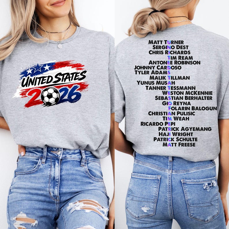 May include: A grey t-shirt with the text "UNITED STATES 2026" and a football graphic. The back of the shirt lists soccer player names. The design uses red, white, and blue colours.