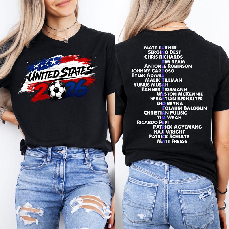 May include: Black t-shirt featuring "UNITED STATES 2026" text and a soccer ball graphic in red, white, and blue. The back of the shirt has a list of names in white. A casual tee for soccer fans.