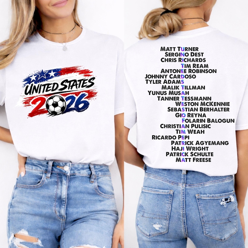 May include: White t-shirt with the text "UNITED STATES 2026" in red, white, and blue, and a soccer ball graphic. The back of the shirt has a list of names. A casual, sporty design.