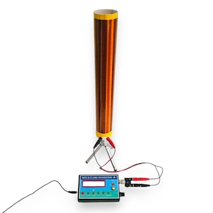 May include: A Rife & Clark generator device featuring a rectangular control box with a digital display, buttons, and a port connected by wires to a tall, cylindrical copper wire coil mounted on a small silver-colored tripod stand with red and black clips.